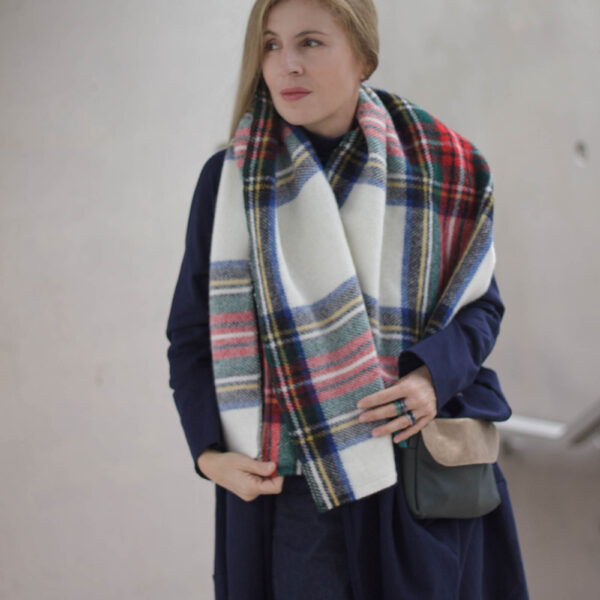 Multicoloured tartan scarf hanging down the front of a navy coat